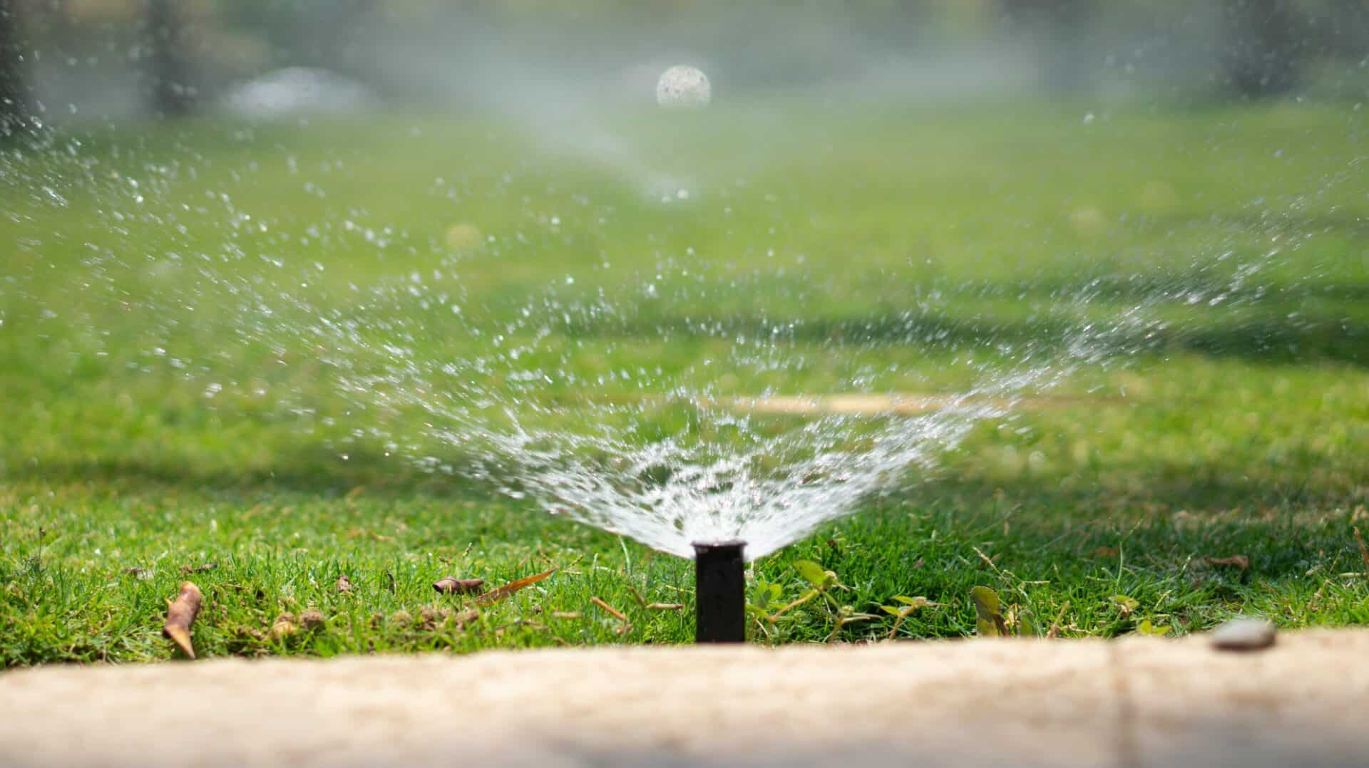 Efficient lawn sprinkler watering the green grass on a golf course during daytime.