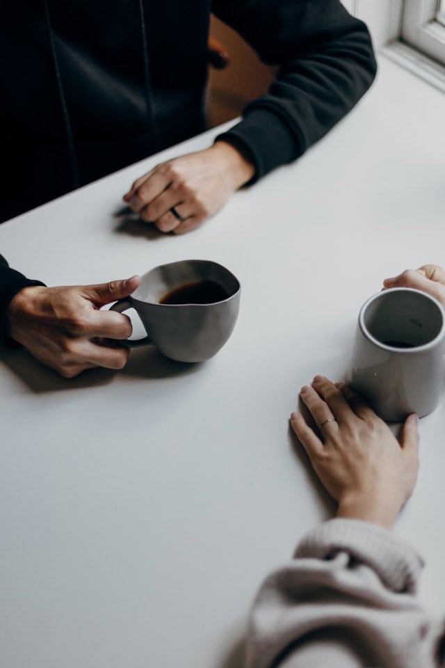 Warm beverage cups on a white table during casual coffee chat or meeting.